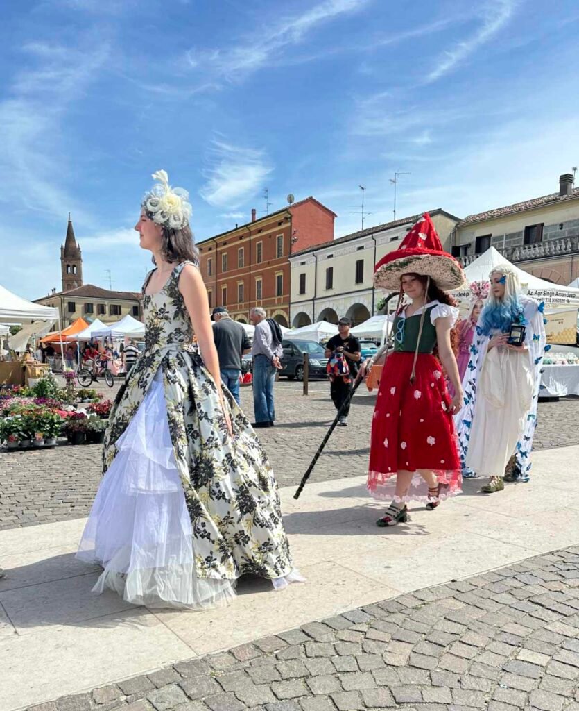 Primo piano di una modella con abito da sposa seguita da Cosplayer floreali in piazza Folengo a San Benedetto Po