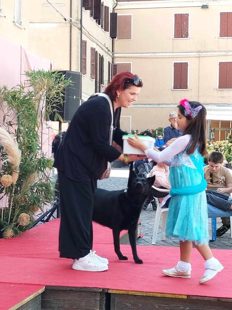 Consegna del primio ad una vincitrice con il suo cane al concorso il collare fiorito